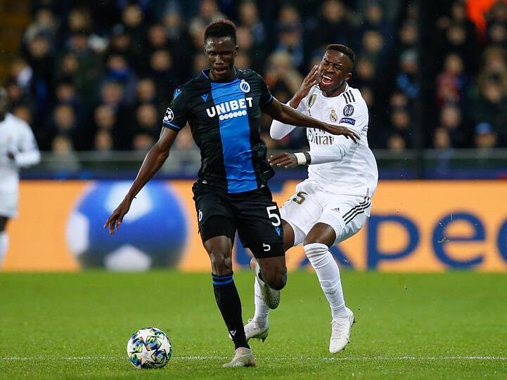 Odilon Kossounou (l) vom FC Brügge und Vinicius Junior (r) von Real Madrid kämpfen um den Ball.