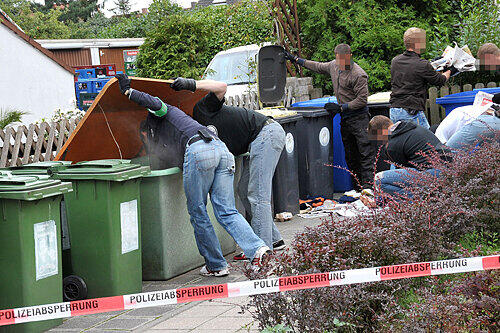 Auf der Suche nach der Tatwaffe und anderen Spuren durchwühlen Polizisten auch die Mülltonnen.