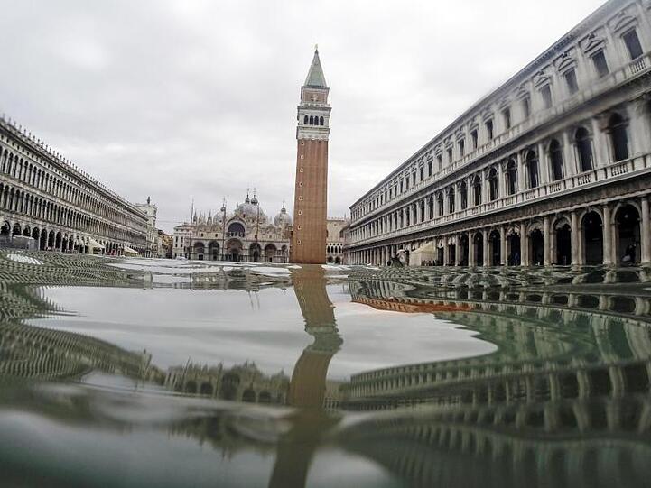 Venedig versinkt: Der Markusturm spiegelt sich im Hochwasser, das den Markusplatz bedeckt.