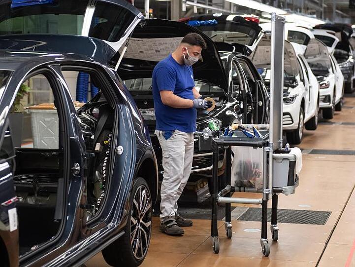 Ein VW-Mitarbeiter steht in der Produktion neben einem Auto im Werk in Wolfsburg.