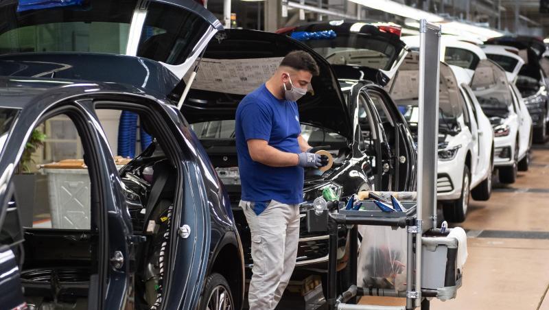 Ein VW-Mitarbeiter steht in der Produktion neben einem Auto im Werk in Wolfsburg.