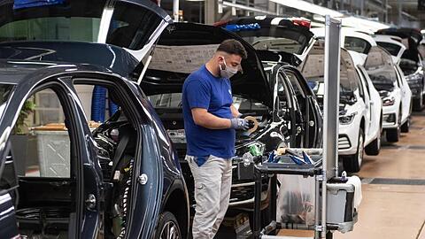 Ein VW-Mitarbeiter steht in der Produktion neben einem Auto im Werk in Wolfsburg.