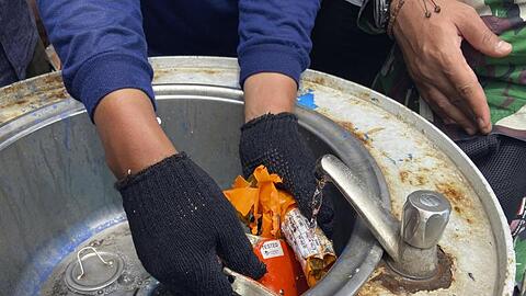 Ein Mitglied der indonesischen Marine inspiziert ein Teil des Flugdatenschreibers.