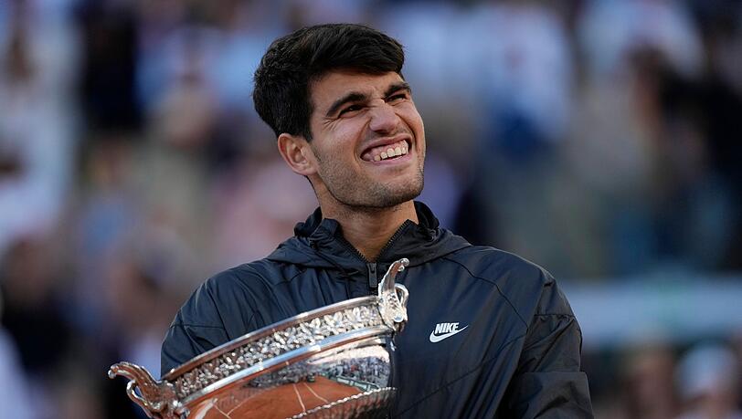 Carlos Alcaraz feiert mit der Trophäe nach seinem Sieg.