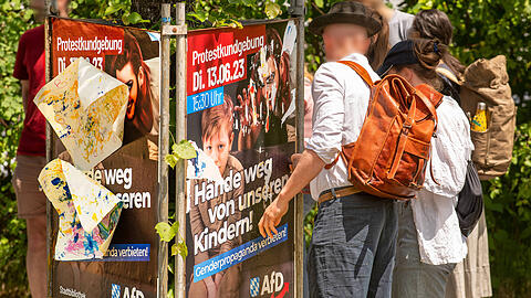 Aufgebrachte Bürger reißen das umstrittene AfD-Plakat ab, das zur Demo gegen eine Dragqueen-Lesung für Kinder in der Stadtbibliothek Bogenhausen aufruft.