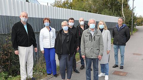 Falk Lamkewitz (links) von den Grünen mit Anwohnern, die gegen die Panzer protestieren. Im Hintergrund die Wellblechwand, die die Teststrecke von der Straße trennt.