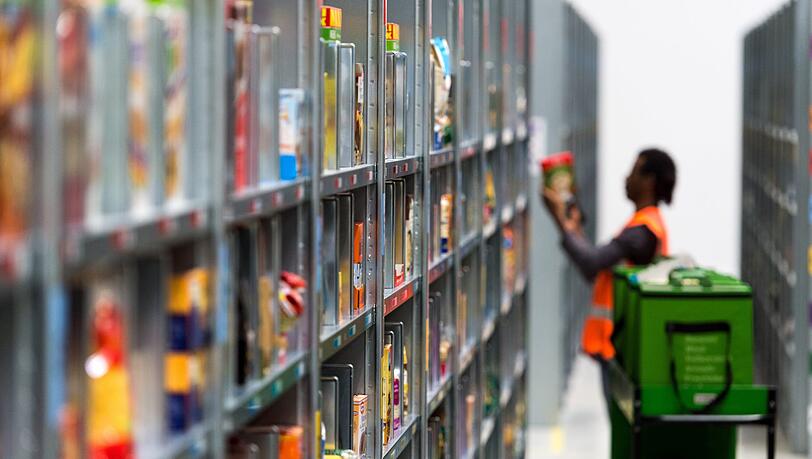 Ein Mitarbeiter des Lebensmittellieferdienstes Amazon Fresh packt im Depot der Firma die bestellten Waren in eine Transporttasche. Ein Mitarbeiter des Lebensmittellieferdienstes Amazon Fresh packt im Depot der Firma die bestellten Waren in eine Transporttasche.