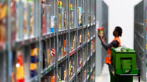 Ein Mitarbeiter des Lebensmittellieferdienstes Amazon Fresh packt im Depot der Firma die bestellten Waren in eine Transporttasche.