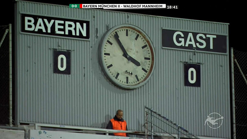 Ein Ordner stellt die Uhr im Grünwalder Stadion auf Winterzeit um - live eingefangen von den Kameras.