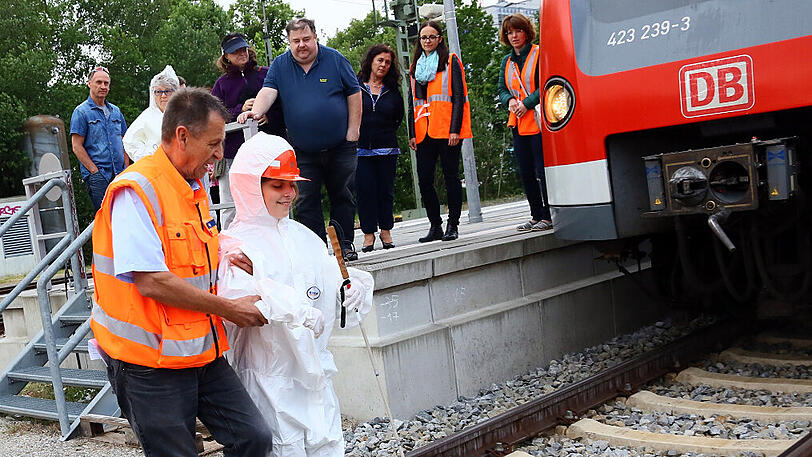 Werner Bögl führt die blinde Lisa R. vorsichtig aufs Gleisbett der S-Bahn.
