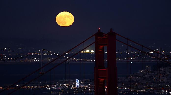 Hinter der Golden Gate Bridge ist am Himmel ein goldfarbener Vollmond zu sehen Hinter der Golden Gate Bridge ist am Himmel ein goldfarbener Vollmond zu sehen