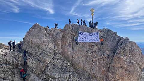 Aktivisten der Organisation Leave No One Behind und des Bayerischen Flüchtlingsrates spannen ein Banner mit der Aufschrift "Asylrecht schützen! Gipfel der Abschottung", um Dobrindts Migrationstreffen zu kritisieren.