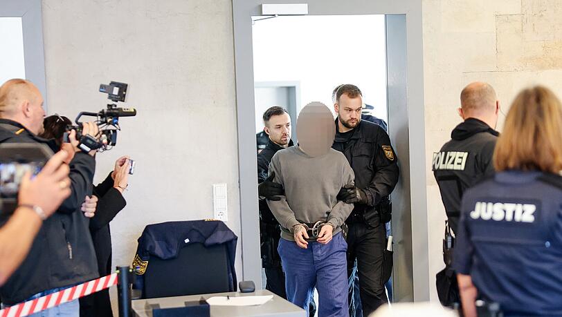 Beim Prozessbeginn vor dem Landgericht um Schüsse aus einem Fluchtauto auf Spezialkräfte der Polizei wird einer der Angeklagten, der Fahrer des Fluchtwagens, von der Polizei in Handschellen und mit Fußfesseln in den Gerichtssaal geführt. Beim Prozessbeginn vor dem Landgericht um Schüsse aus einem Fluchtauto auf Spezialkräfte der Polizei wird einer der Angeklagten, der Fahrer des Fluchtwagens, von der Polizei in Handschellen und mit Fußfesseln in den Gerichtssaal geführt.