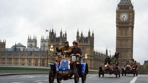 Oldtimer fahren über die Westminster Bridge von London.