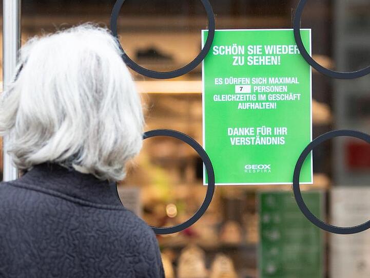 Ein Hinweisschild in Stuttgart weist auf die bislang gültigen Zutrittsbeschränkungen in einem Geschäft hin.
