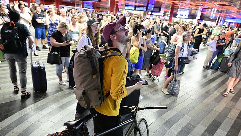 Passagiere sitzen in der Halle des Prager Hauptbahnhofs wähtrend eines Stromausfalls.  Ein Stromausfall hat am Freitag große Teile Tschechiens und der Millionenmetropole Prag lahmgelegt.