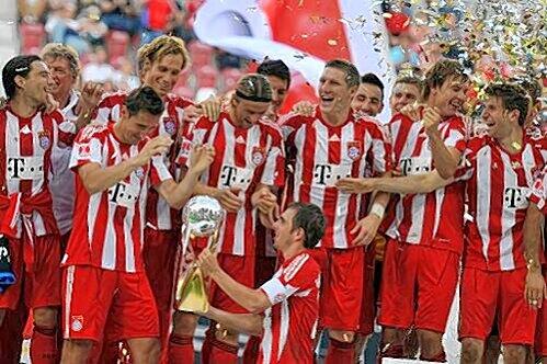 Das erste Ding ist da: Kapitän Philipp Lahm, der Mark van Bommel am Samstag in Augsburg vertrat, präsentiert vor den jubelnden Kollegen den Supercup.