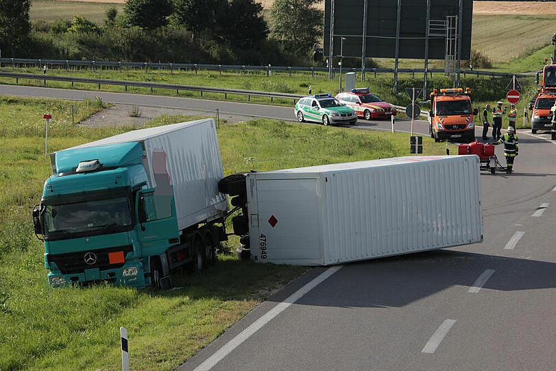 Vermutlich weil er zu schnell auf die Autobahn fährt, kommt ein Laster in der Kurve von der Fahrbahn ab und fährt in die Leitplanke. Sein Hänger kippt um.