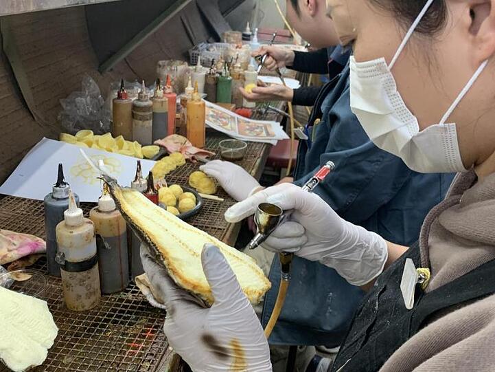 Eine Mitarbeiterin der Firma Iwasaki-Bei beim Bemalen einer Attrappe eines "gegrillten" Hokke-Fisches.