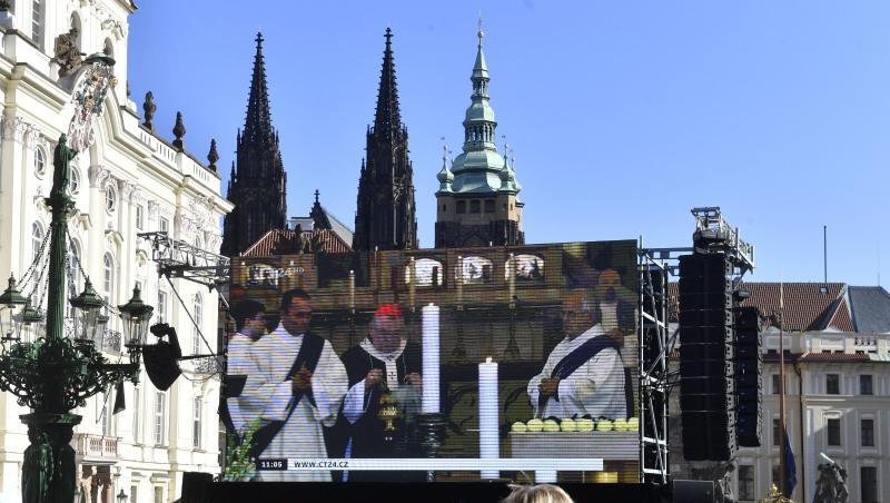 Fans stehen auf dem Hradschiner Platz und schauen auf einen Großbildschirm, auf dem die Trauerfeier für den Sänger Karel Gott im Prager Veitsdom übertragen wird. F.