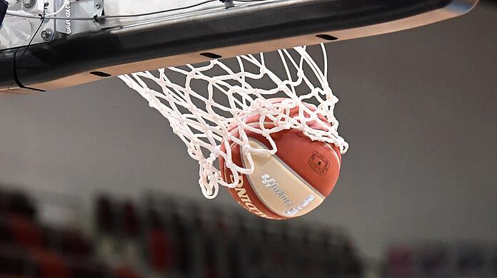 Ein Basketball landet im Korb.