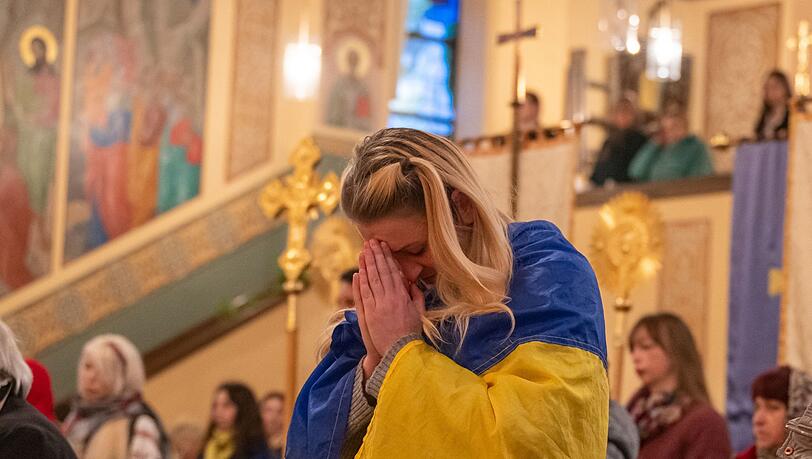 Eine Frau mit einer ukrainischen Flagge nimmt am Auferstehungsgottesdienst teil.