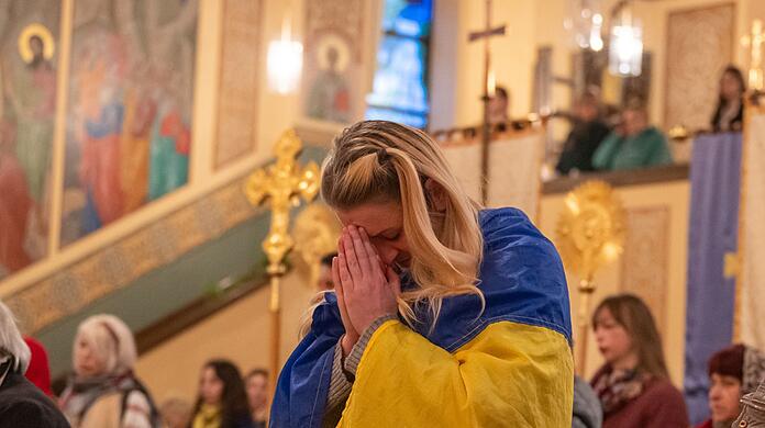Eine Frau mit einer ukrainischen Flagge nimmt am Auferstehungsgottesdienst teil.