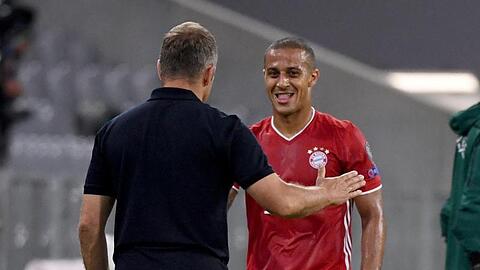 Münchens Trainer Hansi Flick spricht am Spielfeldrand mit Thiago (r).