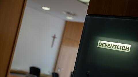 Eine Anzeigetafel weist an einem Sitzungssal auf eine öffentliche Verhandlung hin.