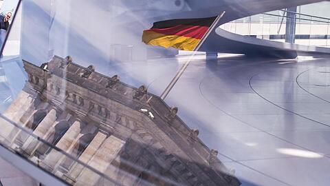 Eine Deutschland-Fahne spiegelt sich in der Kuppel des Reichstagsgebäudes.