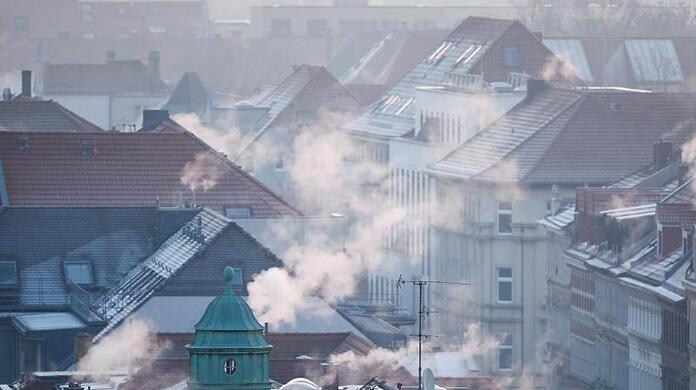 Rauch strömt aus den Kaminen auf den Dächern der Mehrfamilienhäuser im Leipziger Süden an einem kalten Wintermorgen.