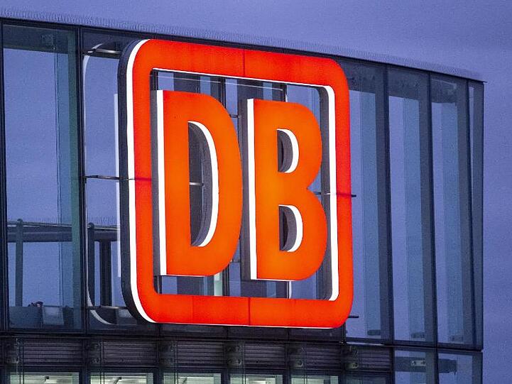 Das Logo der Deutschen Bahn AG ist in der Abenddämmerung am Bahntower am Potsdamer Platz zu sehen.
