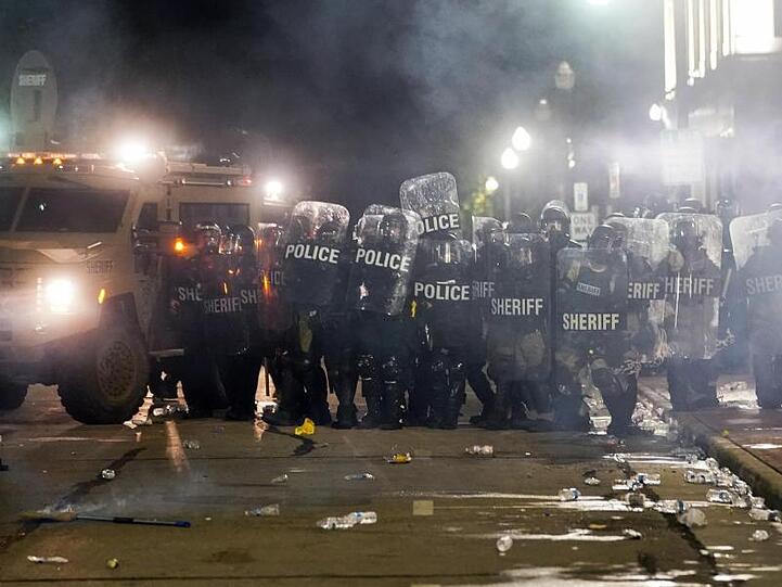 Polizisten stehen dicht zusammen. Als Reaktion auf den Vorfall am Vortag kam es in der Stadt zu Protesten.