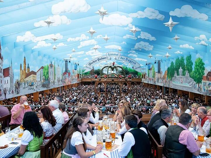 Wiesnbesucher in einem Festzelt unter dem weißblauen Himmel.