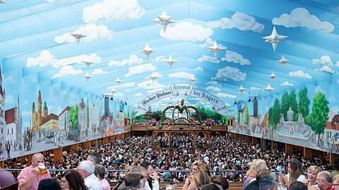 Wiesnbesucher in einem Festzelt unter dem weißblauen Himmel.