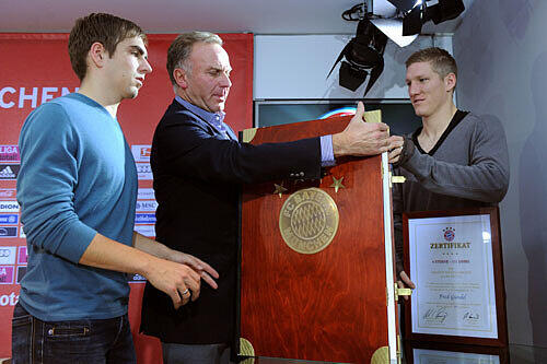 Vorstandsboss Karl-Heinz Rummenigge und die Spieler Philipp Lahm und Bastian Schweinsteiger mit der Bayern-Chronik.