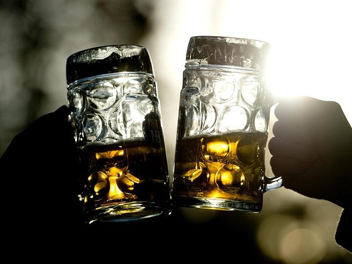 Zwei Frauen stoßen mit Bierkrügen an. Foto: picture alliance / dpa / Illustration