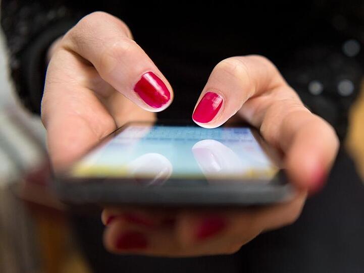 Eine Frau tippt auf einem Smartphone. Foto: Sebastian Gollnow/Archivbild