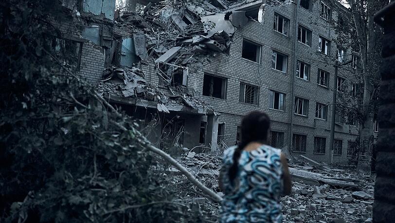 Eine Frau steht inmitten der Trümmer eines Wohnhauses in Mykolajiw, das durch russischen Beschuss zerstört wurde.