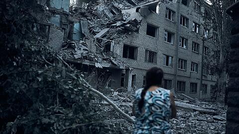 Eine Frau steht inmitten der Trümmer eines Wohnhauses in Mykolajiw, das durch russischen Beschuss zerstört wurde.