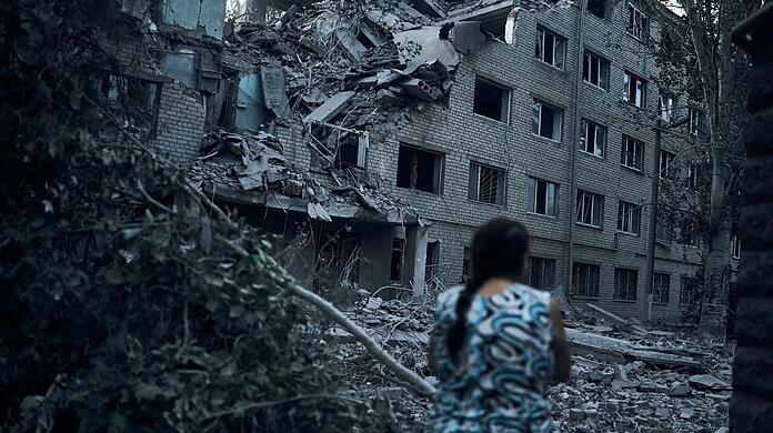 Eine Frau steht inmitten der Trümmer eines Wohnhauses in Mykolajiw, das durch russischen Beschuss zerstört wurde.