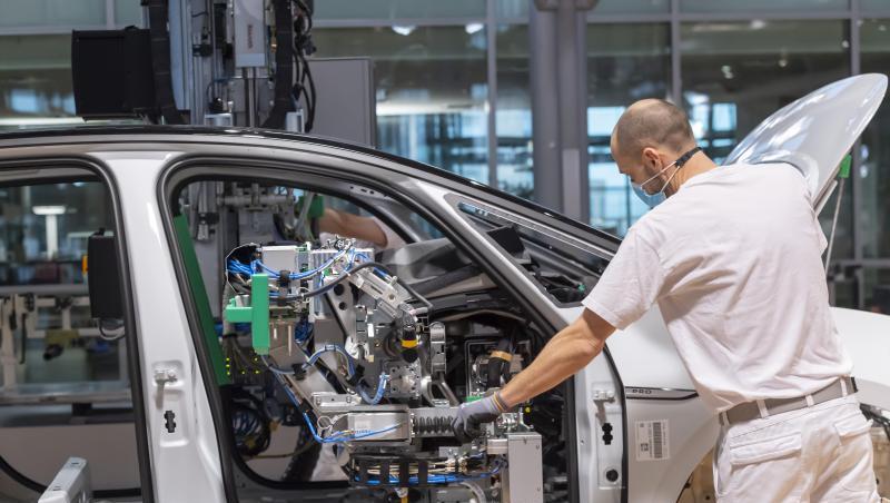 Ein Arbeiter arbeitet mit Mund-Nasen-Schutz an einem Auto.