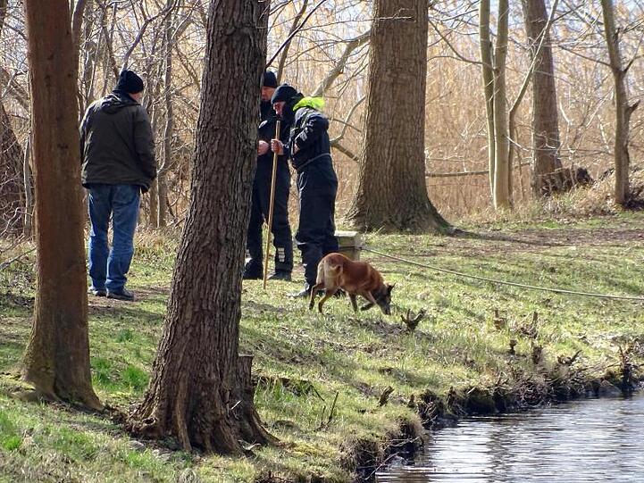 Polizeibeamte mit einem Spürhund suchen am Ufer des Storkower Kanals nahe dem Wolziger See nach Rebecca.