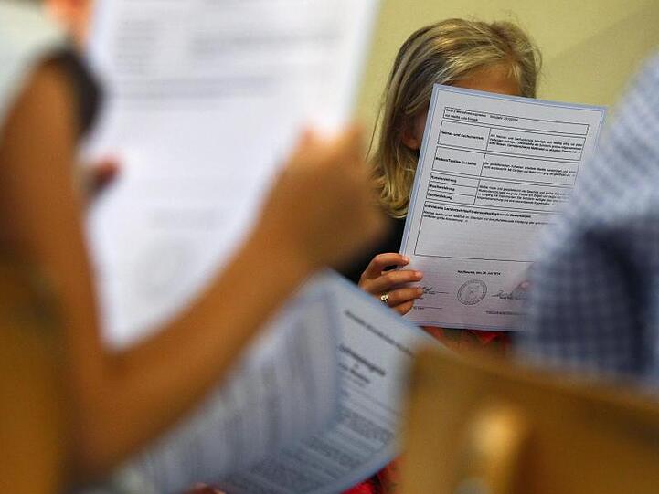 Schüler einer ersten Klasse sitzen in einer Grundschule und lesen ihre Zeugnisse. Foto: Karl-Josef Hildenbrand/dpa/Archiv