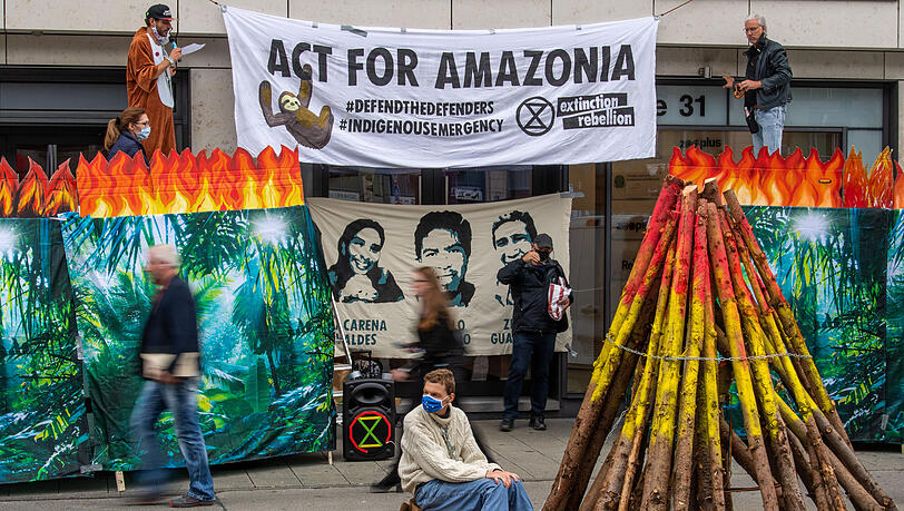 Ein Demonstrant ist auf einem mit symbolischen Flammen verzierten Holzklotz an einem großen symbolischen Feuer festgekettet. Die Gruppe Extinction Rebellion hat mit einer Mahnwache vor dem Brasilianischen Konsulat gegen die Waldbrände im Amazonasgebiet und den Gebietsschwund der indigenen Bevölkerung protestiert. Ein Demonstrant ist auf einem mit symbolischen Flammen verzierten Holzklotz an einem großen symbolischen Feuer festgekettet. Die Gruppe Extinction Rebellion hat mit einer Mahnwache vor dem Brasilianischen Konsulat gegen die Waldbrände im Amazonasgebiet und den Gebietsschwund der indigenen Bevölkerung protestiert.