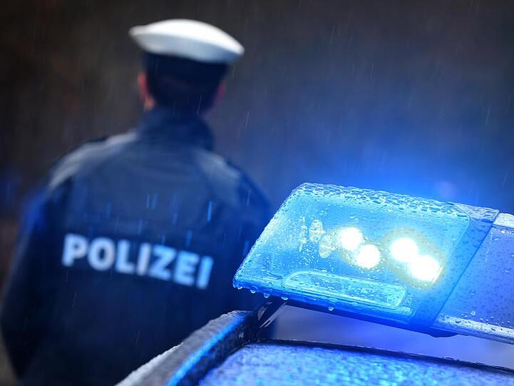 Ein Polizist steht neben einem Streifenwagen. Foto: Karl-Josef Hildenbrand/dpa/Illustration