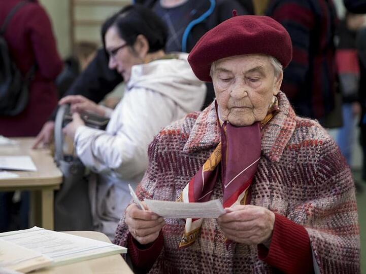 Eine Frau liest den Stimmzettel in einem Wahllokal in Vilnius. Die Wahlbeteiligung lag nach Angaben der Wahlkommission in Vilnius bei 56,5 Prozent.