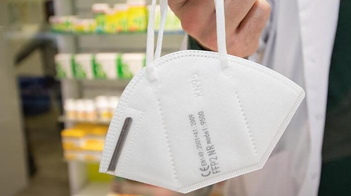 Ein Apotheker hält eine FFP2-Maske.