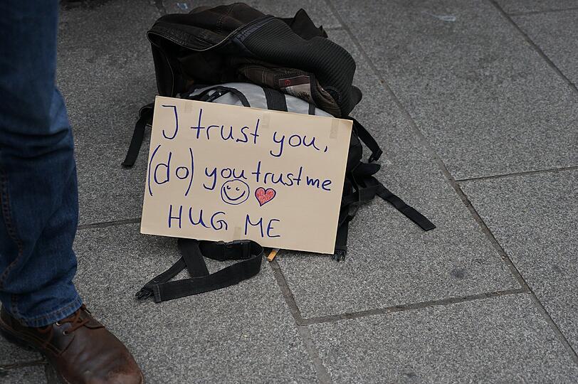 "I trust you (do) you trust me. Hug me." stand auf seinem Schildchen. Zu deutsch: "Ich vertraue Dir, vertrau(st) Du mir. Umarme mich."