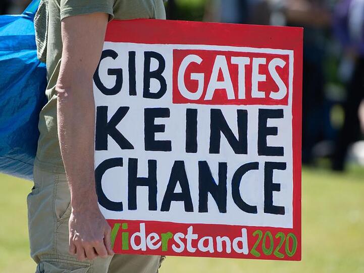 Schild mit der Aufschrift "Gib Gates keine Chance". Foto: Christophe Gateau/dpa/Archivbild